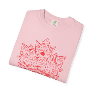 A folded light pink crewneck t-shirt with a red graphic of a maple leaf filled with Canadian provinces and wildlife illustrations, shown on a white background.