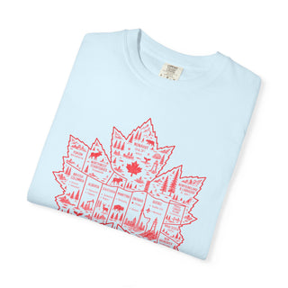 A light blue folded crewneck t-shirt with a red graphic of a map of Canada filled with red nature illustrations, set against a plain white background.