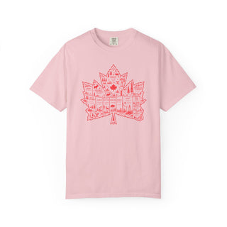 A light pink short-sleeve crewneck t-shirt featuring a red graphic of a Canadian maple leaf filled with illustrations of national landmarks and symbols, displayed on a clean white background.