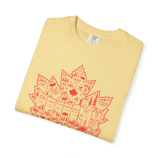 A folded pale yellow t-shirt with a red graphic of a Canadian map outline filled with provincial silhouettes, trees, and wildlife, shown on a white background.