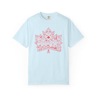 A light blue short-sleeve crewneck t-shirt featuring a red graphic of a maple leaf filled with illustrations of Canadian landmarks and symbols, displayed on a clean white background.